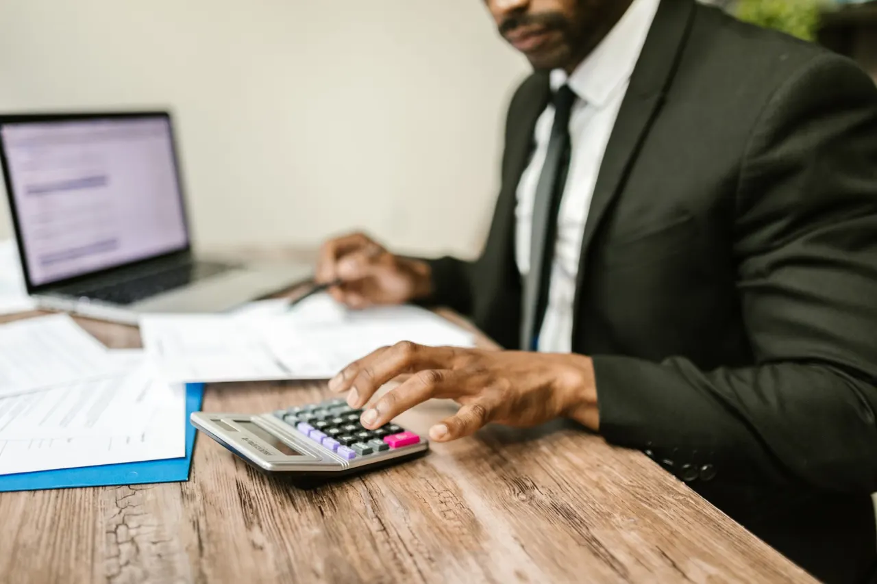 A finance professional working with a calculator and documents